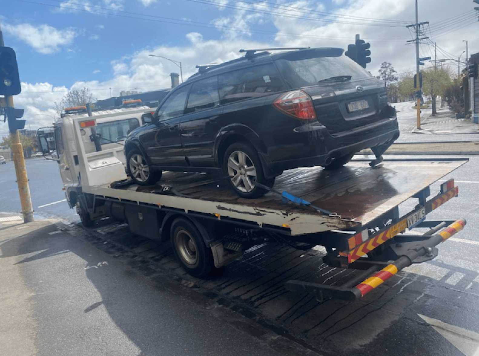 Car towing in Melbourne CBD with a Subaru on a tilt tray.