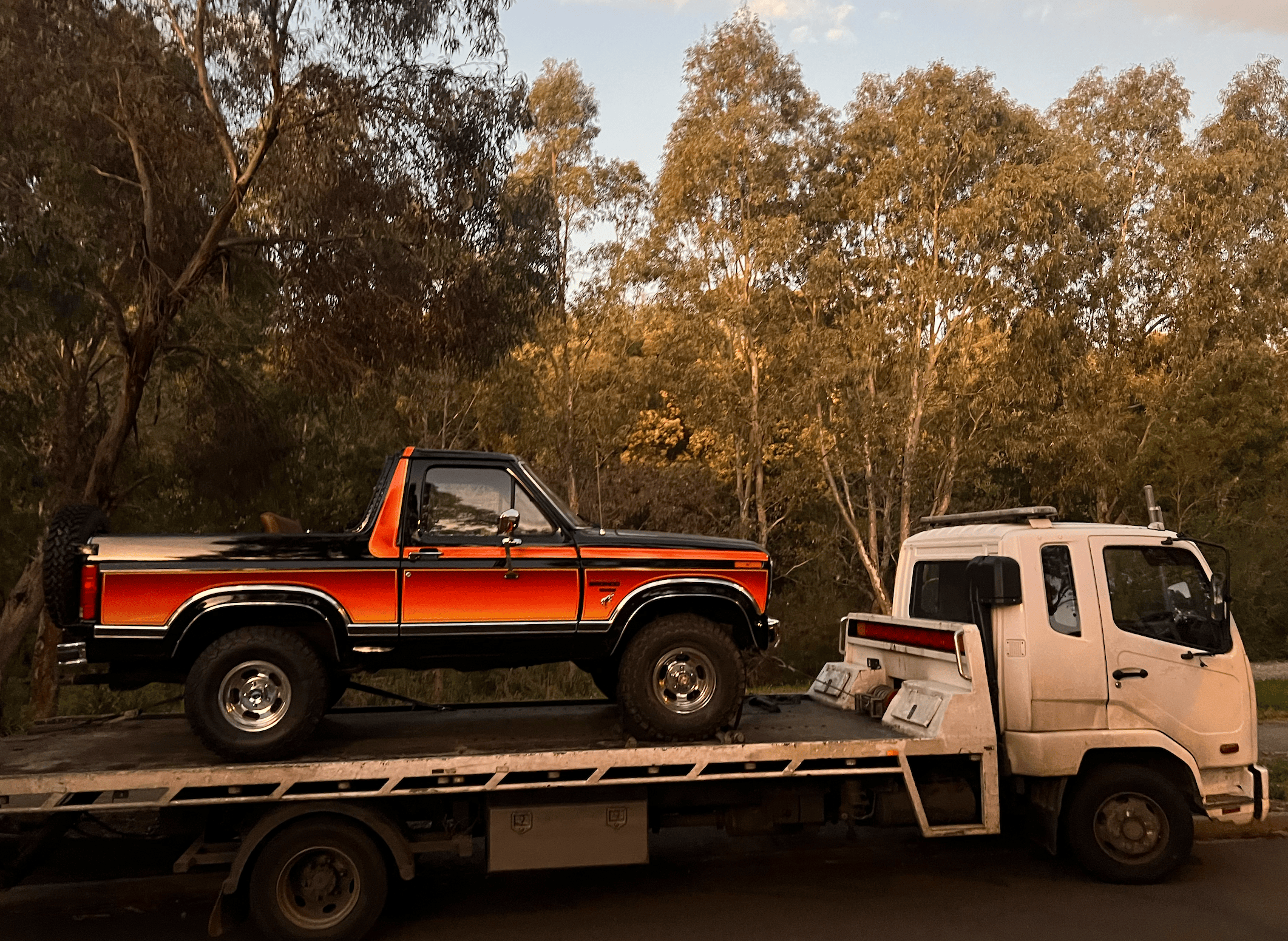 A tilt tray truck towing a car a long distance.