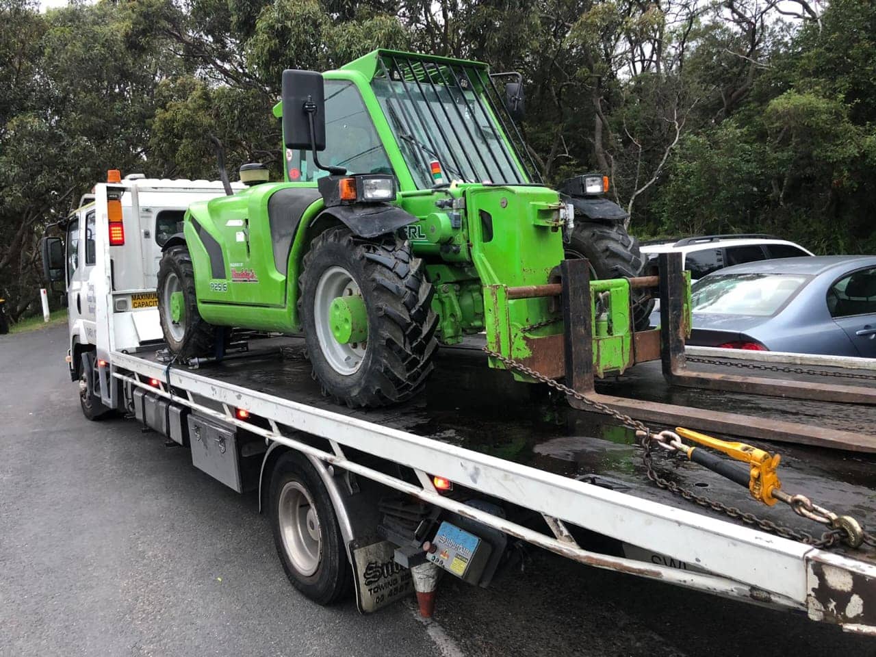 A tow truck towing some farm machinery.